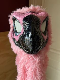 a close up of a stuffed animal wearing a pink furry coat and black eye patch