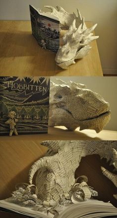 an open book sitting on top of a wooden table next to a paper dragon sculpture