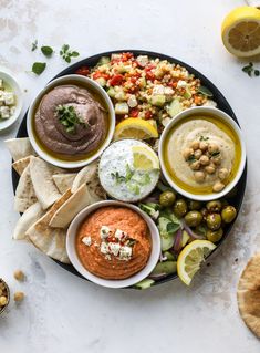 a platter filled with hummus, olives, pita bread and other foods