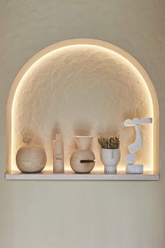 a shelf with vases and other decorative items on it in a white walled room