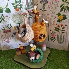 two crocheted stuffed animals sitting on top of a green tray next to plants