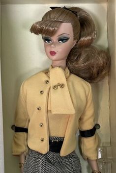 a barbie doll in a box with her hair styled into a high ponytail and wearing a yellow jacket