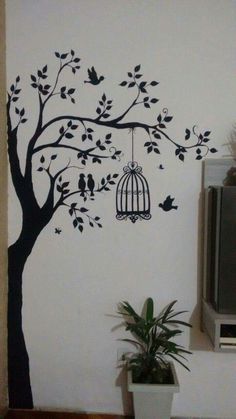 a birdcage hanging from a tree with birds in it and a tv on the wall