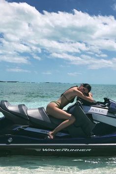 a man and woman riding on the back of a jet ski