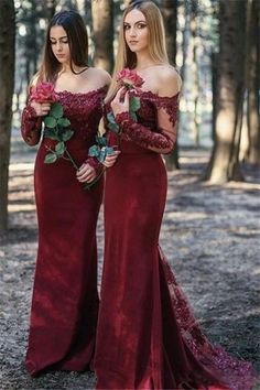 two women in long dresses standing next to each other with roses on their chests