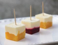 four desserts with toothpicks on them sitting on a white platter, ready to be eaten