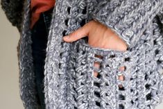 a close up of a person wearing a crocheted jacket with holes in it