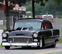 an old black car driving down the road