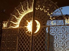 the sun and moon are lit up through an iron gate