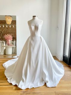 a white wedding dress on display in front of a mirror