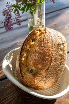 a loaf of bread sitting on top of a plate next to a vase filled with flowers