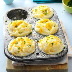 several muffins with cheese and parsley in a muffin tin on a table