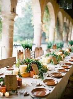 a long table is set up with candles and place settings for an outdoor dinner party