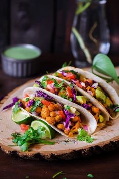 three tacos are sitting on a wooden board