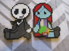 two pieces of perler bead art on top of a white towel with black and red designs