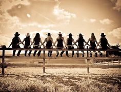 a group of people sitting on top of a wooden bench in the middle of a field