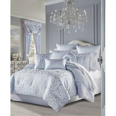 a bed with blue and white comforters in a room next to a chandelier