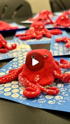 an octopus made out of red clay sitting on top of blue paper with white dots