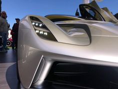 a silver sports car sitting on top of a parking lot next to other cars and people