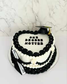 a graduation cake with the words one degree mother written on it and a mortar cap in the shape of a heart