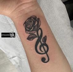 a black and white rose with a treble tattoo on the wrist