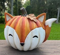 a pumpkin shaped like a fox with its mouth open and eyes closed, sitting on a table