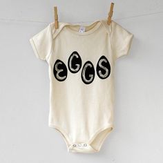 Organic Eggs Onesie This original design is hand printed onto a 100% organic cotton American Apparel onesie, with permanent water-based ink. Kids Tees can be found here.Available colors: Pomegranate Natural Violet Easter Baby Outfit, Chicken Easter, Pizza Shirt, Spring Chicken, Kids Tees, Organic Eggs, Bunny Basket, Eggs Easter, Baby Easter