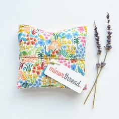 a flowered pouch with a tag on it next to some lavenders