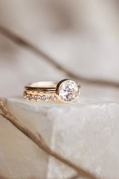 two gold wedding rings with diamonds on top