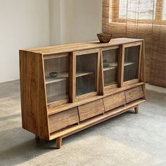 a wooden cabinet sitting on top of a carpeted floor in front of a window