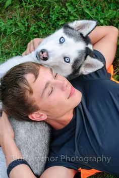 a young man laying on the ground with his husky dog, who is looking up at him