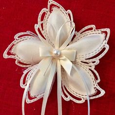 a close up of a white flower on a red cloth with lace and pearls in the center