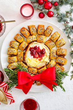 a white plate topped with pastries covered in cranberry sauce and surrounded by christmas decorations