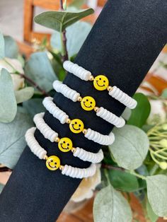 a stack of bracelets with smiley faces on them and some leaves in the background