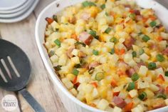 a casserole dish with ham, potatoes and green onions in it on a wooden table