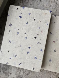 two pieces of paper sitting on top of a table next to each other with blue and white designs