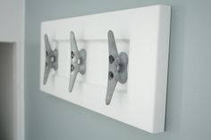 three metal hooks mounted to the side of a white wall next to a light switch