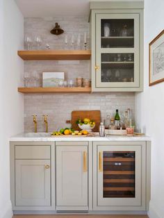 a kitchen with gray cabinets and white tile backsplash, wine glasses on the counter