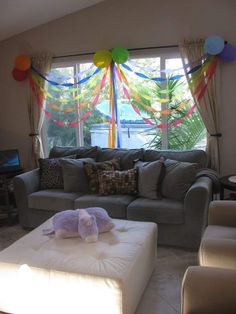 a living room filled with furniture and balloons hanging from the ceiling above it's windows