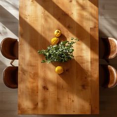 an overhead view of a wooden table with lemons and greenery in the center