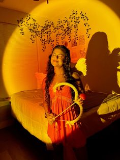 a girl in an orange dress is holding a hoop and standing next to a bed