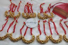 red and gold necklaces are laid out on a white table with a tag in the middle