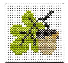 a cross stitch picture with an acorn and leaf design on the front, in white background