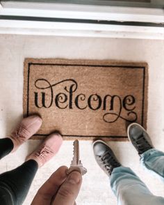 two people standing in front of a welcome mat with the word welcome written on it