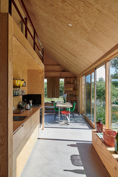 a kitchen and dining area in a house with wood paneling on the walls, windows, and ceiling