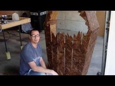 a man sitting in front of a wooden sculpture