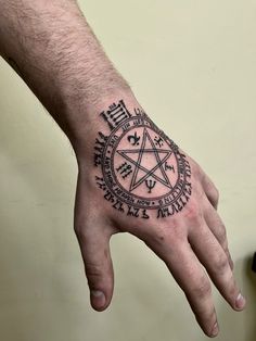 a man's hand with a pentagramil tattoo on the middle of it