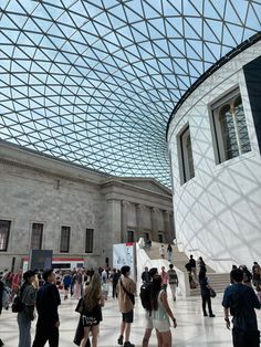 many people are walking around inside the building with glass roofing on it's sides