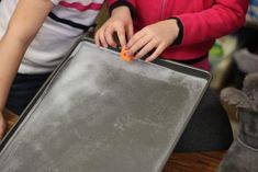 two young children are playing with a metal tray