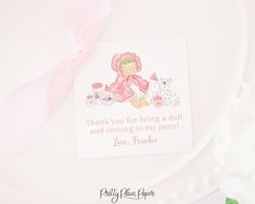 a thank card with a pink ribbon on top of a white plate and flowers in the background